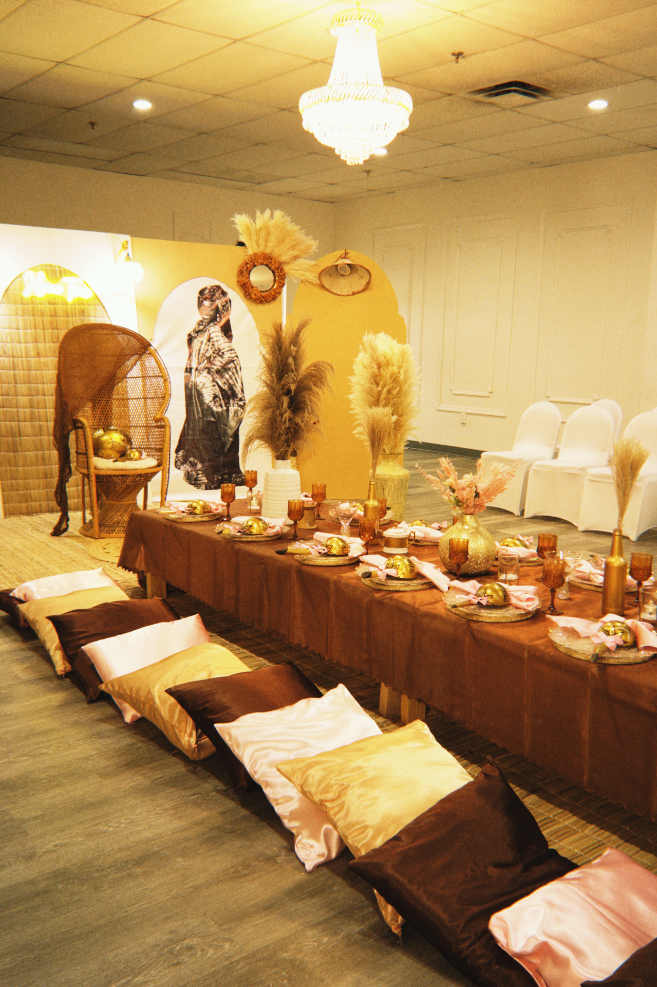 Wide Henne Time room view with floor seating, layered woven backdrops, pampas arrangements, and a richly styled banquet table.