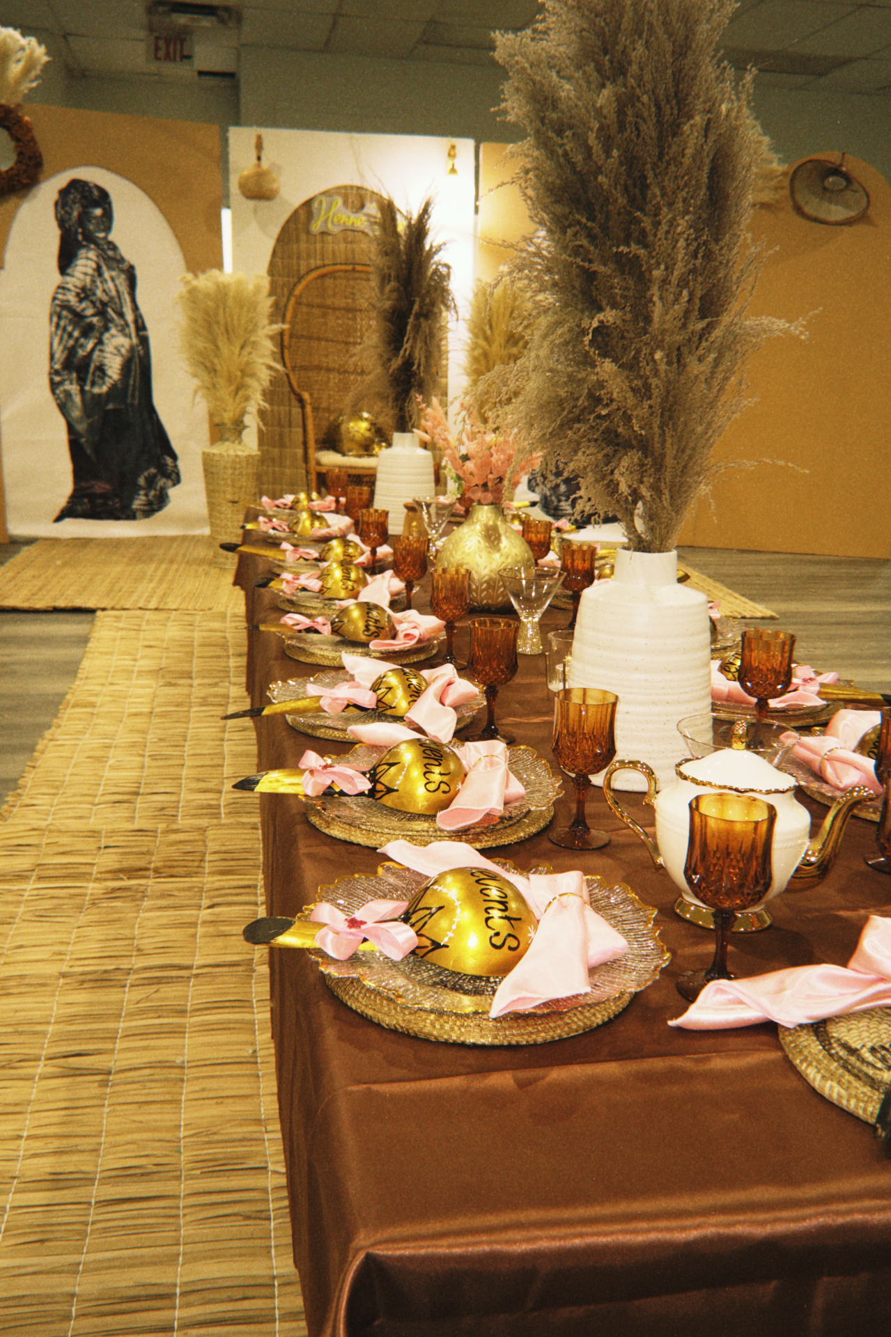 Long Henne Time banquet table with pampas, amber glassware, gold place settings, and layered neutral backdrops.
